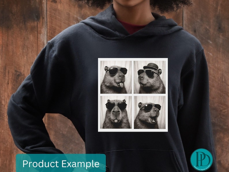 May include: Black hoodie with a square graphic featuring four black and white images of a capybara wearing sunglasses and a hat. The words "Product Example" are at the bottom.