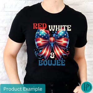 May include: Black t-shirt featuring a patriotic bow design in red, white, and blue, with the words "RED WHITE & BOUJEE" in a stylized font. The bow has a star-spangled pattern and striped ribbons.