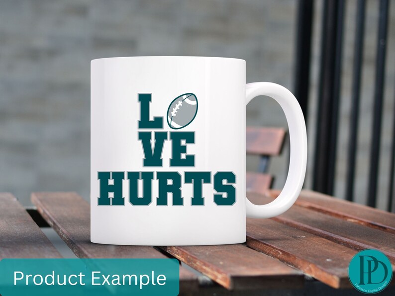 K&ouml;nnte beinhalten: Eine wei&szlig;e Keramik-Kaffeetasse mit einem blaugr&uuml;nen Design, auf dem "Love Hurts" mit einer Fu&szlig;ballgrafik steht.