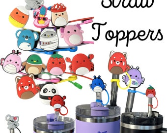 May include: A collection of colorful silicone straw toppers with various animal and food designs. The toppers are attached to reusable straws and fit on top of two stainless steel tumblers with the word "STANLEY" printed on them. The tumblers are purple and black.