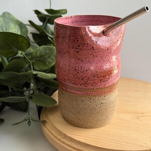 Puede incluir: Una taza de cer&aacute;mica rosa y marr&oacute;n con una pajita de acero inoxidable. La taza tiene un esmalte moteado y un dise&ntilde;o ondulado.