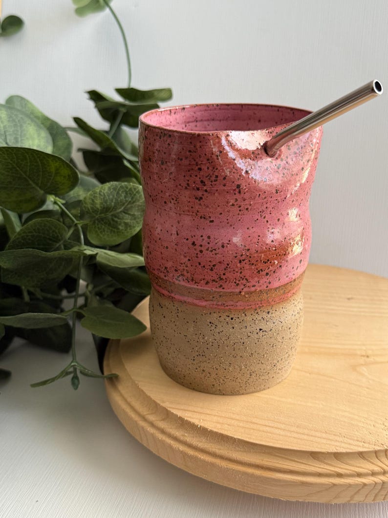 Puede incluir: Una taza de cer&aacute;mica rosa y marr&oacute;n con una pajita de acero inoxidable. La taza tiene un esmalte moteado y un dise&ntilde;o ondulado.