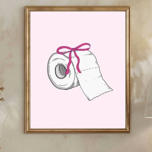 Könnte beinhalten: Eine weiße Toilettenpapierrolle mit einem rosa Band darum gebunden. Die Rolle befindet sich auf einem rosa Hintergrund.