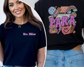 May include: Black t-shirt with a pink "PARA" graphic on the back. The graphic includes a rainbow, a pencil, a star, a smiley face apple, and other school-themed elements. The front of the shirt has the text "Mrs. Miller" in pink.