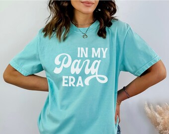May include: A light blue t-shirt with the text "In My  Pang Era" in white. The shirt is made of a soft, comfortable material.