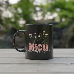 May include: Black ceramic mug with a pink floral design and the text "NICU Lauren" on it.