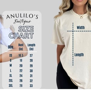 Puede incluir: Tabla de tallas para camisetas con medidas en pulgadas. La tabla muestra las medidas de busto, ancho y largo para las tallas XS a 3XL. La tabla tambi&eacute;n incluye el texto "Anulilo's Boutique" y "Comfort Colors CTM".