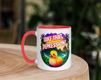 May include: White ceramic mug with a red rim. The mug has a colorful graphic of a yellow rubber duck in a tropical setting with the text "Take That, Depression!" printed on it.