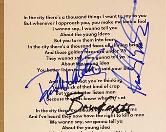 May include: A white paper with handwritten lyrics and blue ink signatures. The text includes song lyrics about young ideas and city life. The signatures are in blue ink.