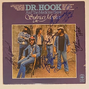 Puede incluir: Portada del álbum "Dr. Hook and The Medicine Show - Sylvia's Mother". La portada presenta un grupo de cinco hombres con atuendos de mezclilla, con firmas. El título del álbum y los títulos de las canciones son visibles sobre un fondo púrpura.