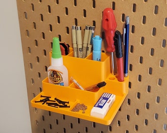 May include: Orange plastic organizer with multiple compartments for holding small items. It is mounted on a pegboard wall and contains pens, pencils, glue, a screwdriver, and other tools.