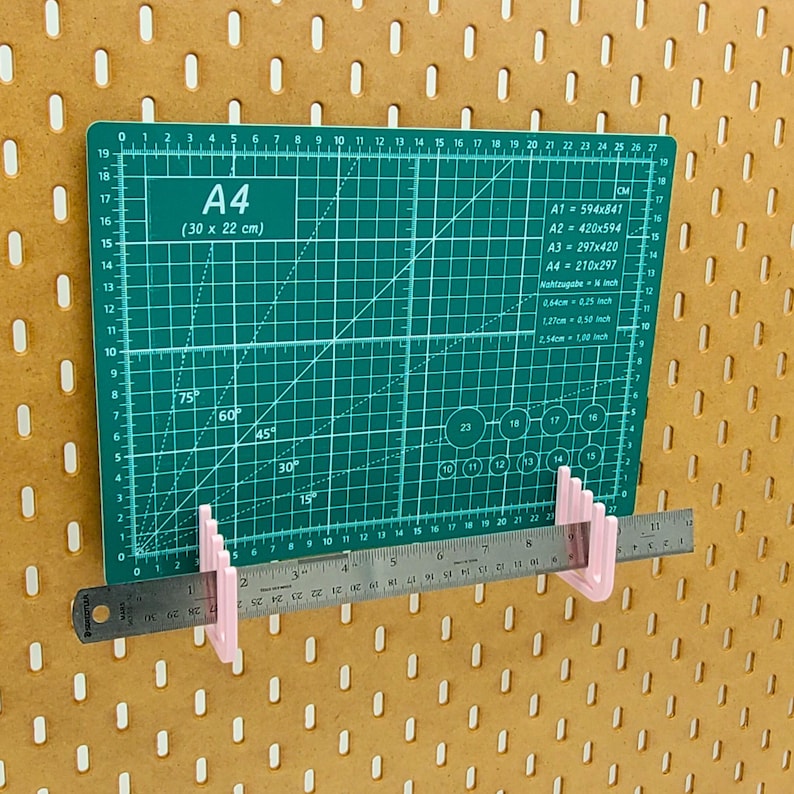 Op de afbeelding: Een groene snijmat met witte markeringen en een liniaal die aan de onderkant is bevestigd. De mat is gemarkeerd met "A4 (30 x 22 cm)" en heeft hoekmarkeringen voor 15, 30, 45, 60 en 75 graden. De liniaal is gemarkeerd in inches en centimeters.