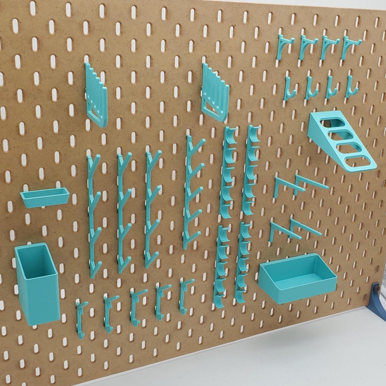 Puede incluir: Un tablero de clavijas con varios ganchos, estantes y organizadores de pl&aacute;stico azul turquesa. El tablero de clavijas est&aacute; hecho de madera y tiene un acabado marr&oacute;n.