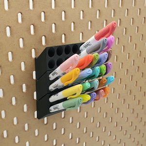 May include: A black plastic wall-mounted organizer with 24 compartments holds a variety of colorful Sharpie brand permanent markers.