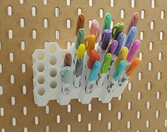 May include: A white plastic organiser with 18 compartments holds a variety of coloured markers. The markers are arranged in a rainbow pattern.