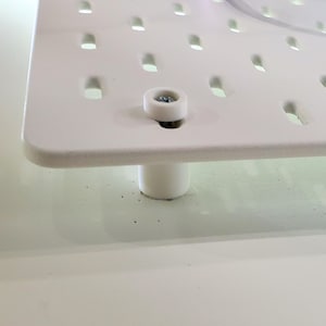 May include: White plastic base with a round, white plastic foot. The base has a grid of small holes and a screw in the center.