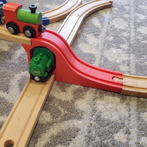 Könnte beinhalten: Ein hölzernes Spielzeug-Zugsset mit einer roten und grünen Lokomotive, die über eine rote und hölzerne Schiene fährt.
