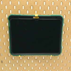 May include: A green tablet case with a black screen. The case has a yellow tab on the top.