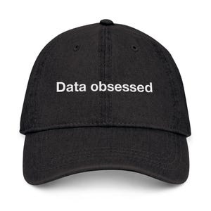 Peut inclure: Casquette de baseball noire avec le texte blanc "Data obsessed" brodé sur le devant. La casquette a une visière incurvée et une fermeture à sangle en tissu à l'arrière. Un chapeau décontracté.