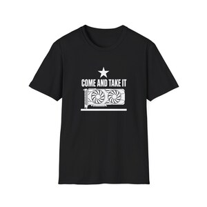 以下が含まれることがあります： 白いグラフィックのコンピューターグラフィックカードと、その上に「COME AND TAKE IT」というテキスト、テキストの上に星が描かれた黒いTシャツ。 シャツはクルーネックで半袖です。