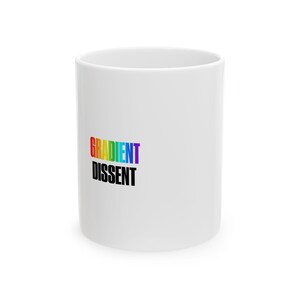 May include: A white ceramic mug featuring the word GRADIENT in a multi-colored rainbow spectrum font stacked above the word DISSENT printed in bold black capital letters on the side of the cylindrical vessel.