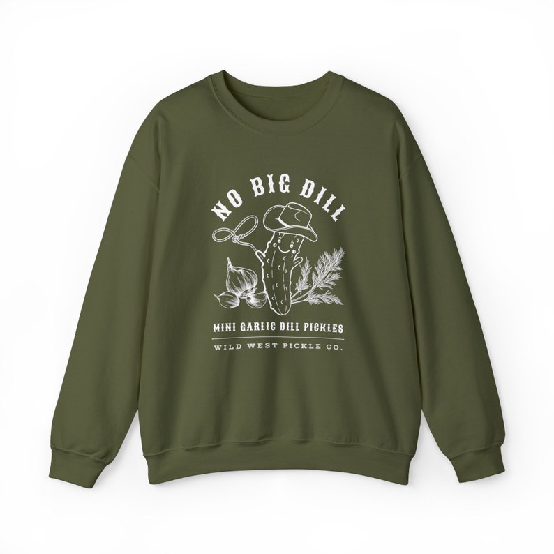 Peut inclure: Sweat-shirt vert olive avec un motif blanc repr&eacute;sentant un cornichon portant un chapeau de cowboy, un lasso, de l'ail et des brins de verdure. Le texte sur le sweat-shirt se lit "NO BIG DILL" et "MINI GARLIC DILL PICKLES WILD WEST PICKLE CO."