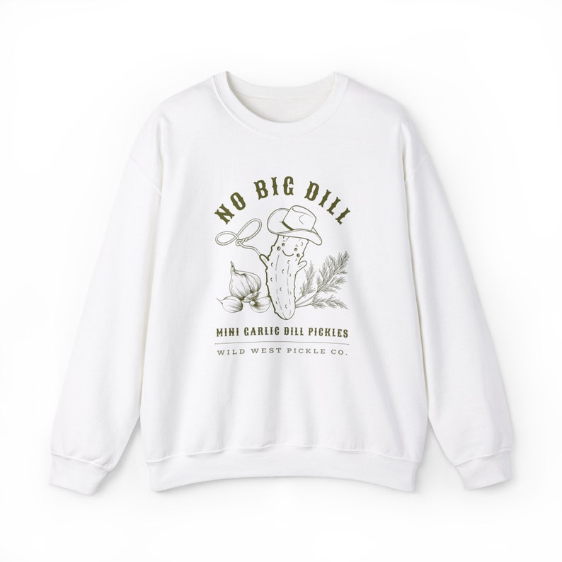 Peut inclure: Sweat-shirt blanc avec un dessin vert d'un cornichon souriant portant un chapeau de cow-boy, un lasso et de l'ail. Le texte indique "NO BIG DILL" et "MINI GARLIC DILL PICKLES WILD WEST PICKLE CO."