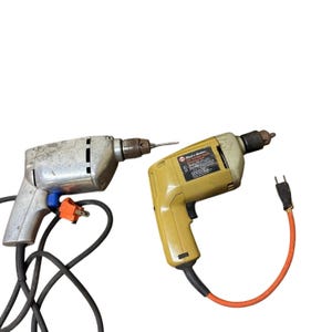 May include: Two vintage power drills. One is silver with a blue switch and orange plug. The other is yellow with a black cord and orange extension. Both have drill bits attached and are on a white background.
