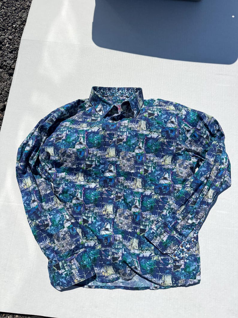 May include: A long-sleeved button-down shirt with a colorful abstract pattern in shades of blue, green, and white. The shirt has a classic collar and buttoned cuffs. The fabric appears to be lightweight.