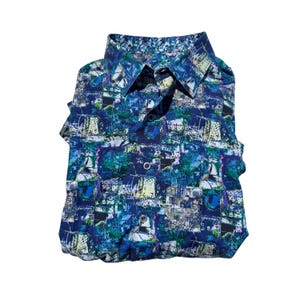 May include: Folded button-down shirt with a vibrant abstract pattern in shades of blue, green, and white. The shirt features a classic collar and button closure. The interior collar lining has a decorative pattern.