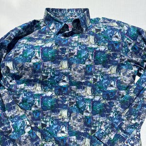 May include: Long-sleeved button-down shirt with a vibrant, abstract pattern in shades of blue, green, and white. The shirt features a classic collar and buttoned cuffs. The overall design gives the shirt a modern and artistic look.