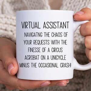 May include: White ceramic mug with black text that reads "VIRTUAL ASSISTANT NAVIGATNG THE CHAOS OF YOUR REQUESTS WITH THE FINESSE OF A CIRCUS ACROBAT ON A UNICYCLE MINUS THE OCCASIONAL CRASH!"
