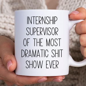 May include: White ceramic coffee mug with black text that reads "Internship Supervisor of the Most Dramatic Shit Show Ever".