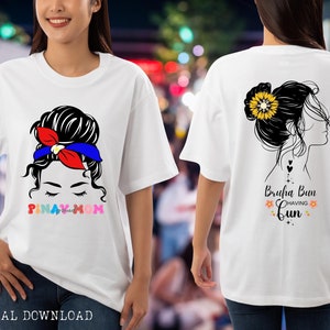 May include: Two white t-shirts with a graphic design of a woman with a messy bun. The left shirt has the text "Pinay Mom" in rainbow letters. The right shirt has the text "Bruha Bun Having Fun" with flowers.