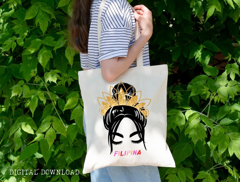 May include: A white tote bag with a black and gold illustration of a woman with a bun and a crown. The text "FILIPINA" is printed in pink, yellow, and blue letters.