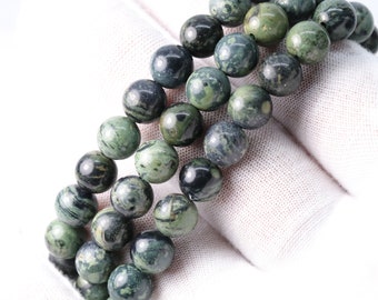 May include: A strand of green and black gemstone beads. The beads are round and have a marbled pattern.
