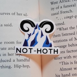 May include: A blue and white sticker with a mountain range design and the text "NOT-HOTH" in white letters. The sticker is placed on a page of a book with text about Morse code.