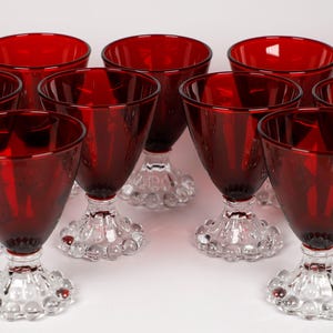 May include: Set of twelve ruby red glass goblets with clear glass stems and bases. The bases have a textured, bubble-like design.