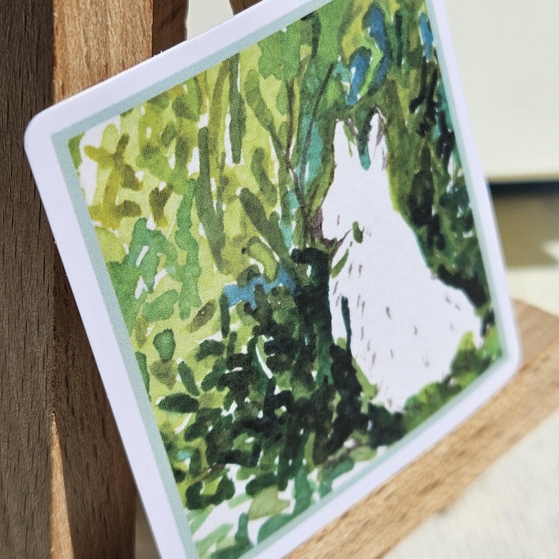 May include: A watercolor painting of a white rabbit peeking out from behind green foliage. The rabbit is facing to the right and is partially obscured by the leaves. The background is a soft green and blue.