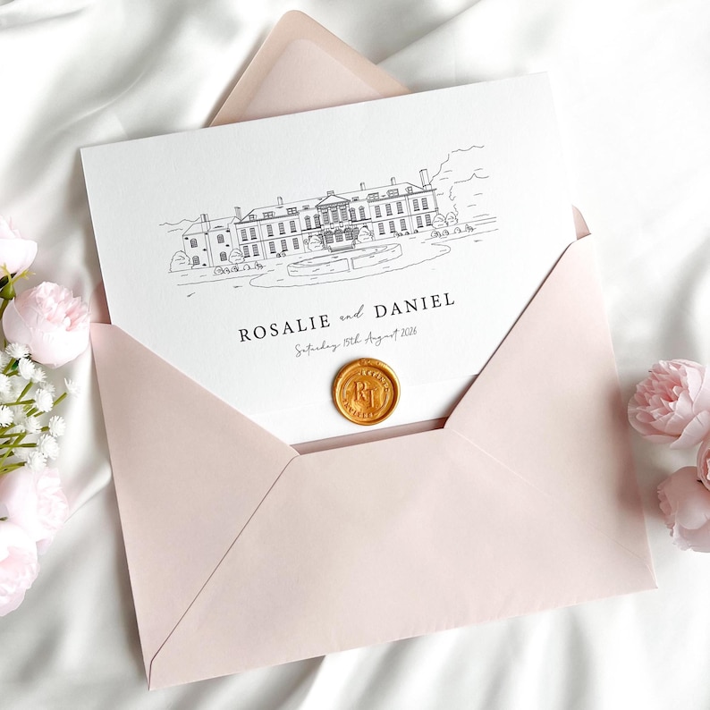 May include: A light pink envelope holds a white card with a black line drawing of a building and the names "Rosalie and Daniel" with a date. A gold wax seal is on the card. The envelope is on a white surface with pink flowers.