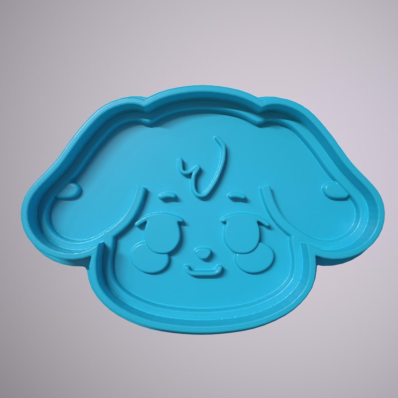May include: A light blue plastic cookie cutter shaped like a cartoon dog with big eyes and a small nose.