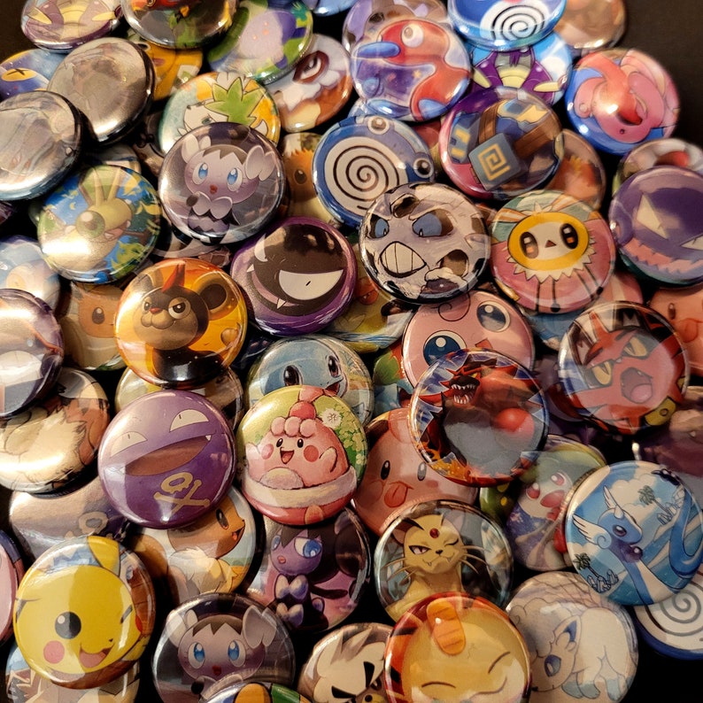 May include: A collection of colorful, round pinback buttons featuring various cartoon character designs. The buttons are primarily circular, with glossy surfaces and vibrant colors. The designs include a variety of characters, with a focus on a popular animated franchise.