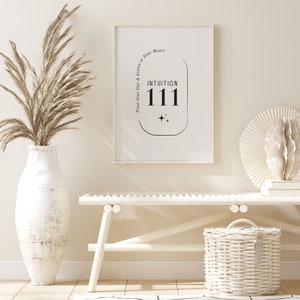 K&ouml;nnte beinhalten: Ein gerahmter Druck mit den Worten "INTUITION 111" in Schwarz, mit dem Text "Trust Your Gut & Listen to Your Heart" dar&uuml;ber. Der Druck wird in einem hellen Raum mit einer wei&szlig;en Bank, einem geflochtenen Korb und einer gro&szlig;en Vase mit getrockneten Pflanzen ausgestellt.