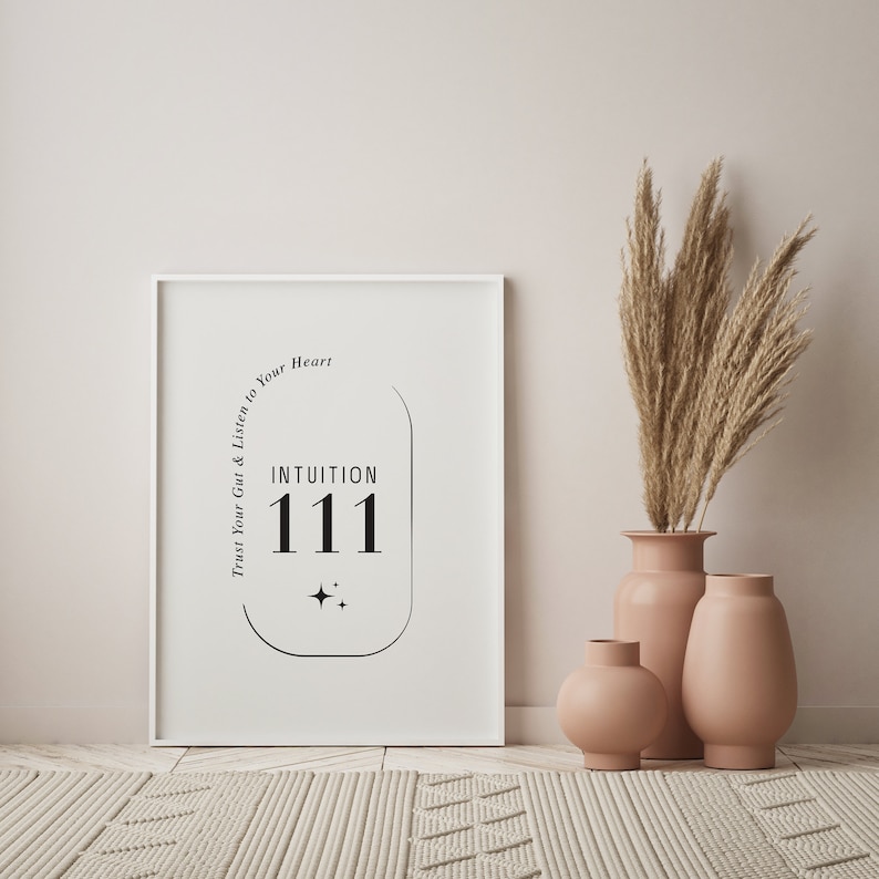 K&ouml;nnte beinhalten: Ein wei&szlig; gerahmter Druck mit dem Text "INTUITION 111" in Schwarz, begleitet von einer Sternengrafik. Der Druck steht an einer Wand, neben drei pfirsichfarbenen Vasen und einer Vase mit getrocknetem Pampasgras. Der Text "Trust Your Gut & Listen to Your Heart" ist ebenfalls vorhanden.