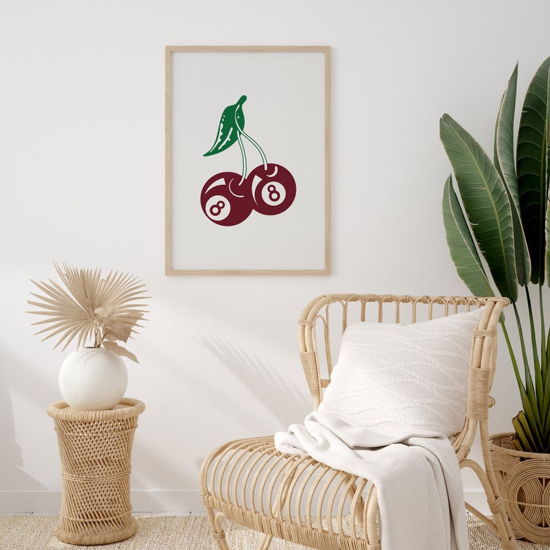 May include: A framed print of a red cherry with a green stem and leaves. The cherry is made up of two 8-ball pool balls.