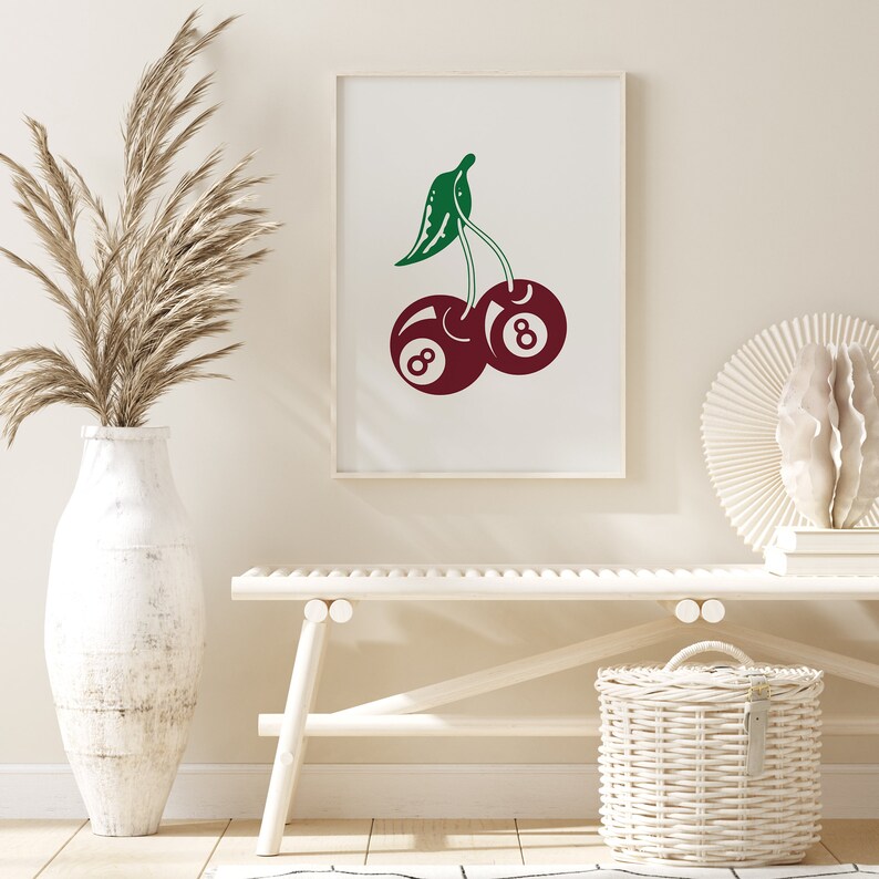 May include: A white framed print with a red and green illustration of two cherries. The cherries are shaped like the number eight billiard balls.