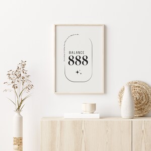 May include: A framed print with a white background and black text that reads "BALANCE 888" inside a rounded rectangle. The text "Everything is Falling into Place as It's Meant to Be." is written vertically along the right side of the rectangle.