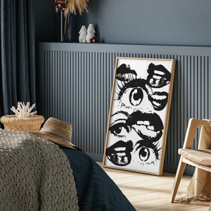 Puede incluir: Impresi&oacute;n de arte abstracto en blanco y negro con una serie de ojos y labios. La impresi&oacute;n est&aacute; enmarcada en un marco de madera natural y cuelga de una pared azul.