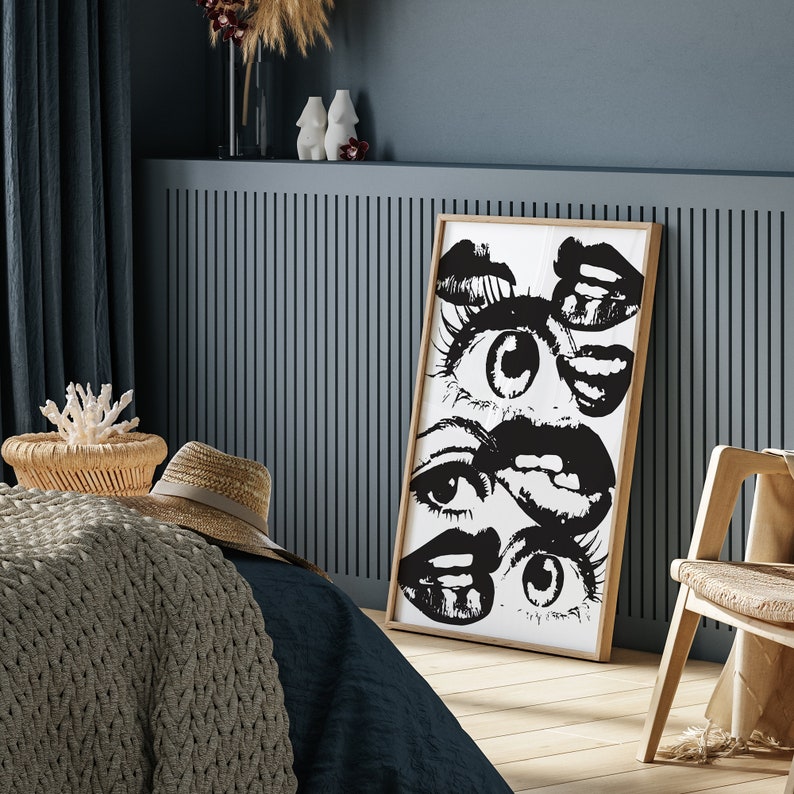 Puede incluir: Impresi&oacute;n de arte abstracto en blanco y negro con una serie de ojos y labios. La impresi&oacute;n est&aacute; enmarcada en un marco de madera natural y cuelga de una pared azul.