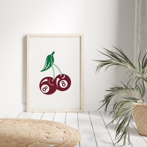 May include: A framed print of a red cherry with a green stem and leaf. The cherry is a stylized image of a billiard ball with the number 8 on it.